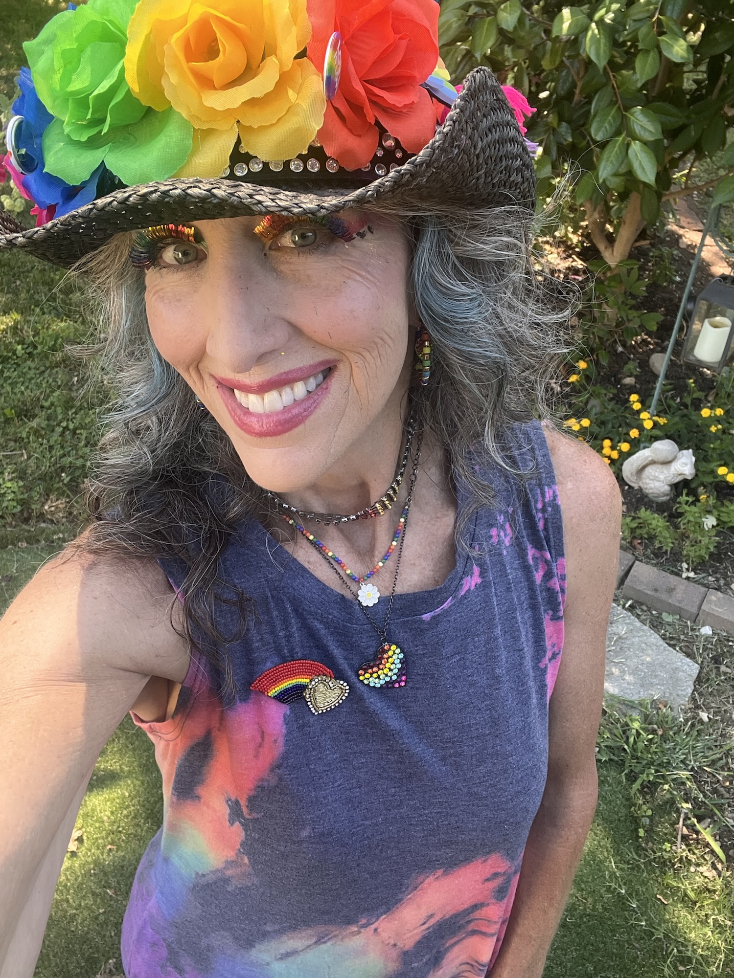 Me wearing hat with rainbow flowers and rainbow tie-dye dress, along with rainbow jewelry