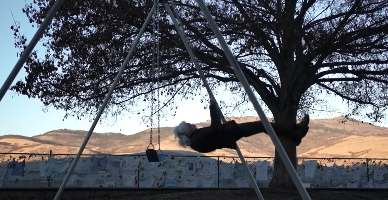 Dot Fisher-Smith, age 95, swinging high beneath a large tree with the hills of Ashland, Oregon, in the distance.