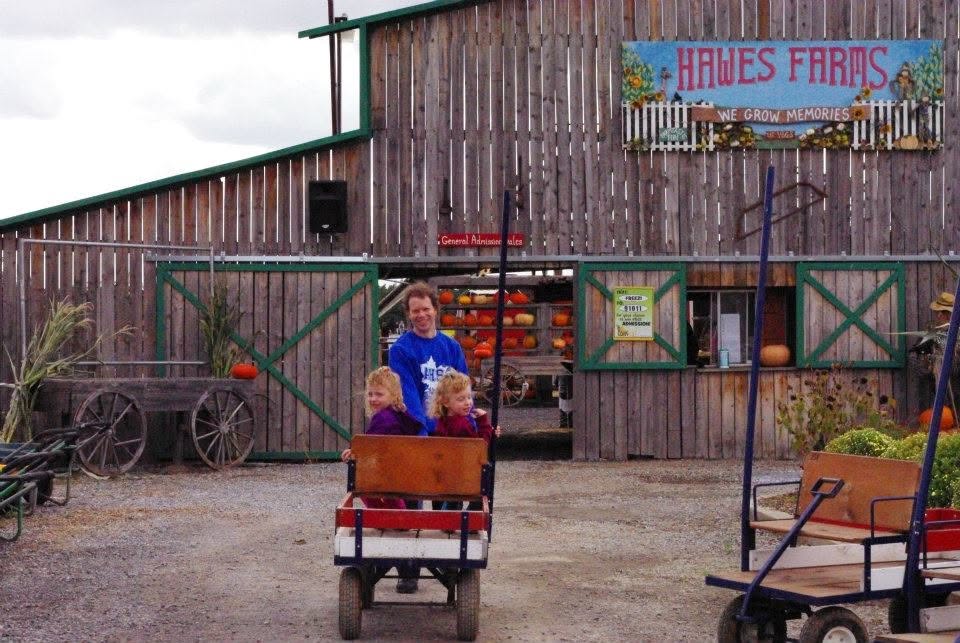 Entrance to Hawes Farm back on October 1, 2011. Wagon been pulled with two curly hair twin girls inside. A sign reads Hawes Famr and then near it another sign that reads We Grow Memories.